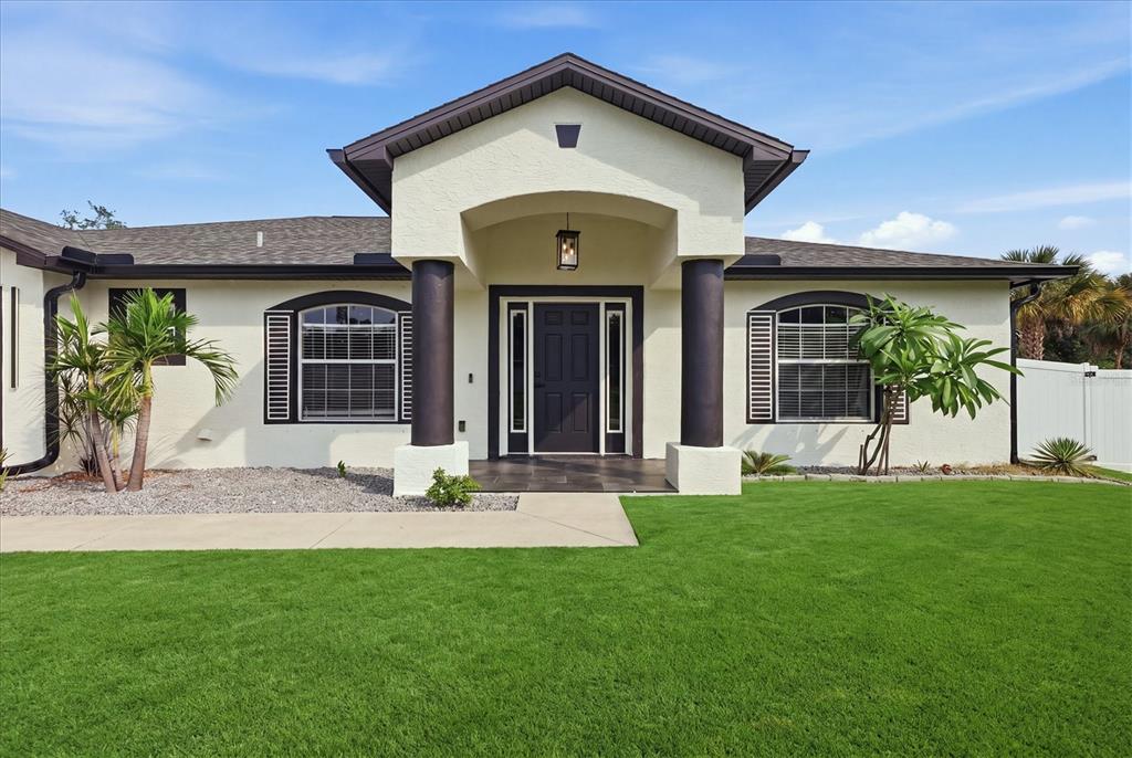 A single-story house with a cream stucco exterior, dark trim, and a covered front entryway — 281 PEMBROKE DRIVE, PORT CHARLOTTE, FL