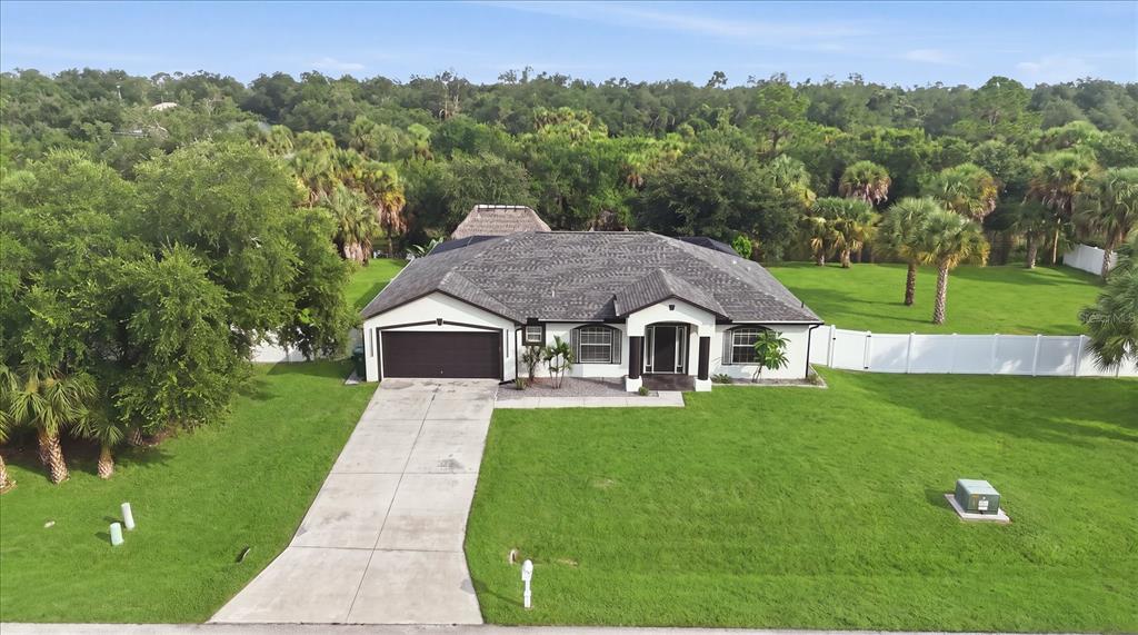 An aerial view of a single-story house with a dark roof, garage, and large lawn — 281 PEMBROKE DRIVE, PORT CHARLOTTE, FL