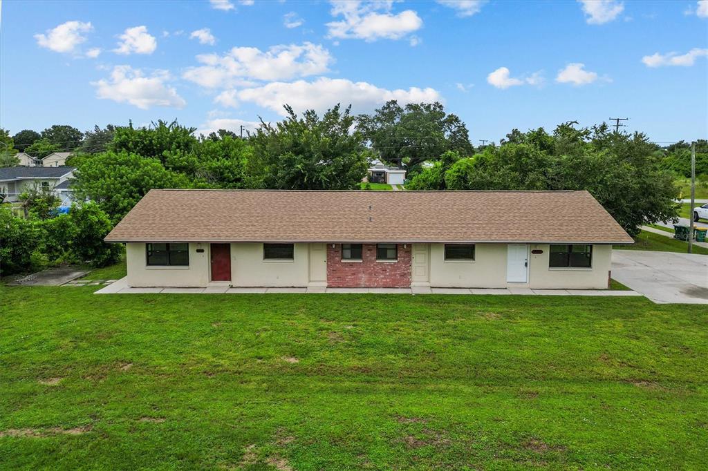An exterior view of a single-story duplex with a brown shingled roof and lawn — 27242 SUNNYBROOK ROAD, PUNTA GORDA, FL