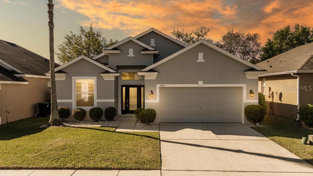 A single-story suburban house with a gray stucco exterior, a two-car garage, and a front lawn — 9973 CYPRESS KNEE CIRCLE, ORLANDO, FL