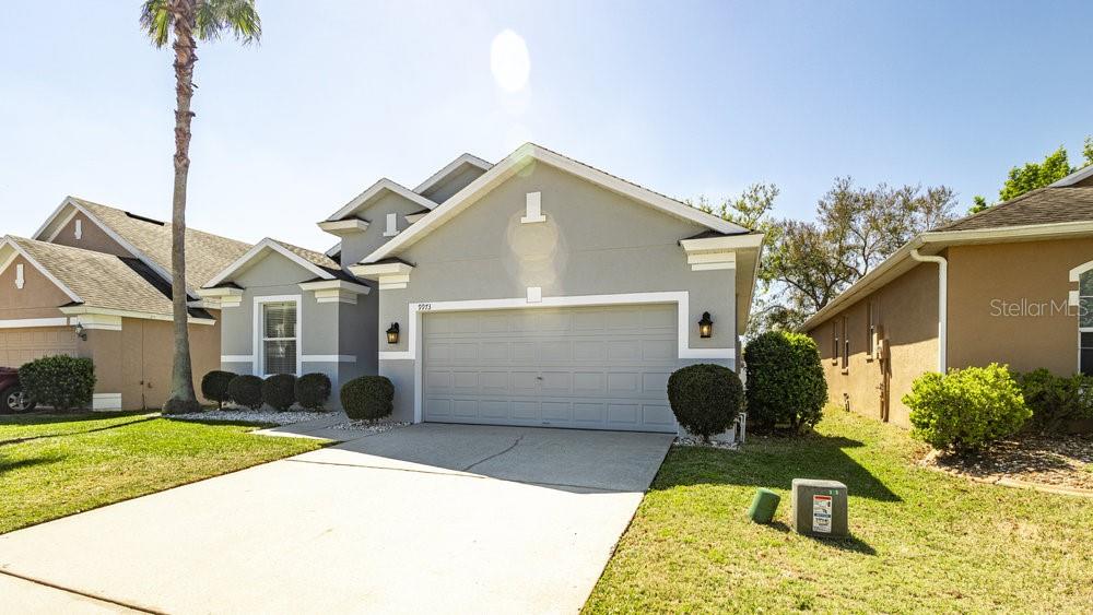 A single-story house with a gray stucco exterior, a two-car garage, and a palm tree — 9973 CYPRESS KNEE CIRCLE, ORLANDO, FL
