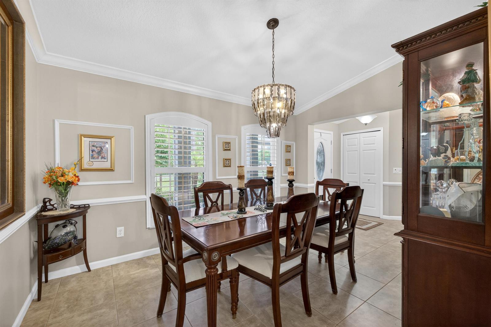 A dining room features a wooden table with six chairs, a chandelier, and a display cabinet — 5606 Silver Oak Drive, Fort Pierce FL 34982, FORT PIERCE, FL