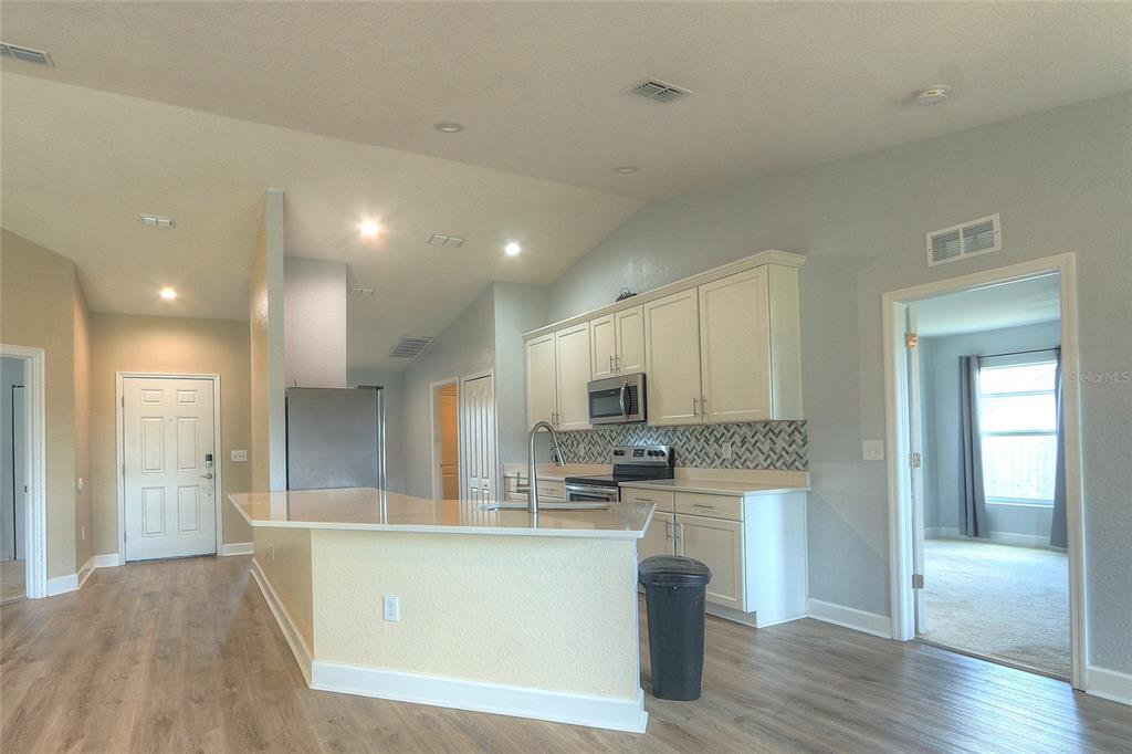 A kitchen with white cabinets, a breakfast bar, and stainless steel appliances — 110 PLUM AVENUE, FROSTPROOF, FL