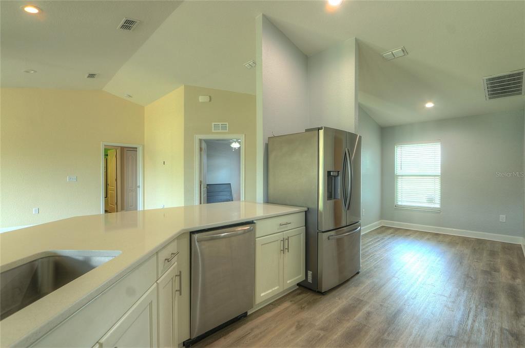 A kitchen features white cabinets, stainless steel appliances, and light wood-look flooring — 110 PLUM AVENUE, FROSTPROOF, FL