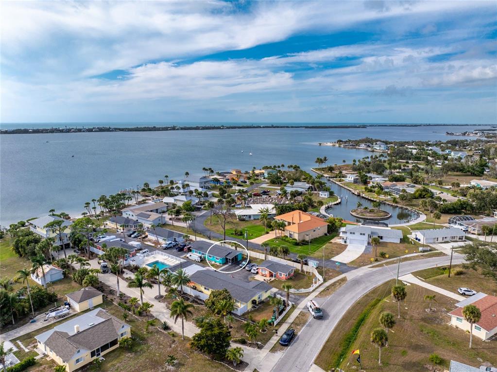 An aerial view shows a teal house circled in a coastal neighborhood near the water — 470 S MCCALL ROAD UNIT 10, ENGLEWOOD, FL