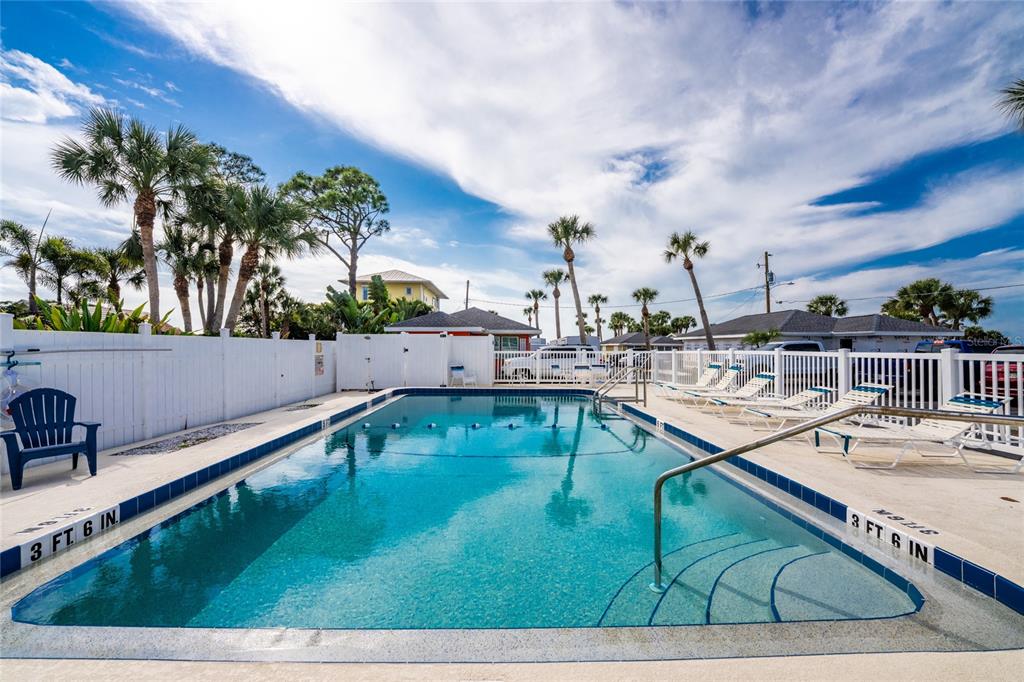 An outdoor swimming pool with a white fence and palm trees under a blue sky — 470 S MCCALL ROAD UNIT 10, ENGLEWOOD, FL