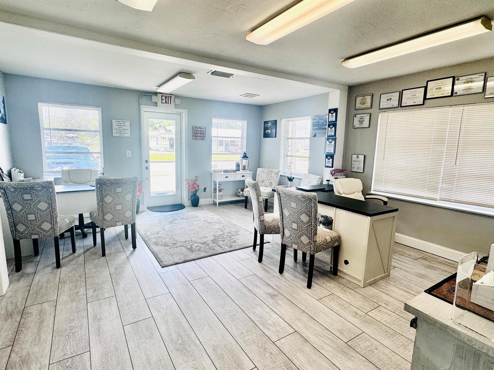 An office space features light wood-look tile flooring, two desks with patterned chairs, and large windows — 206 SW 3rd Street, Okeechobee FL 34974, OKEECHOBEE, FL
