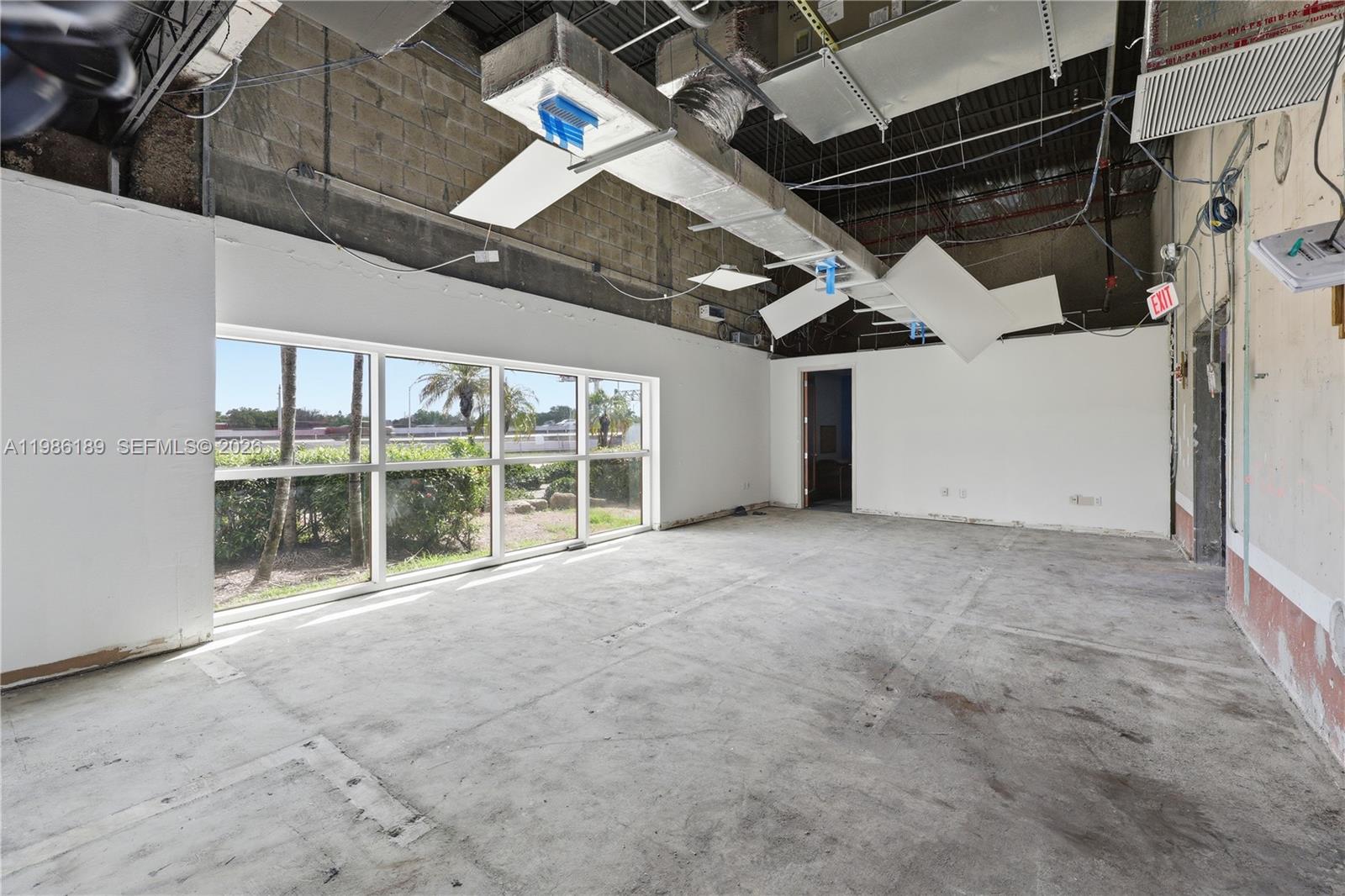 An unfinished commercial space features exposed ceiling ducts, concrete floors, and large windows — 2950 N 28th Ter, Hollywood FL 33020, HOLLYWOOD, FL