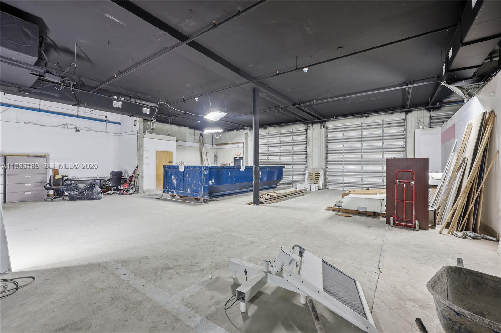 An industrial warehouse space features a concrete floor, exposed black ceiling, and two roll-up doors — 2950 N 28th Ter, Hollywood FL 33020, HOLLYWOOD, FL