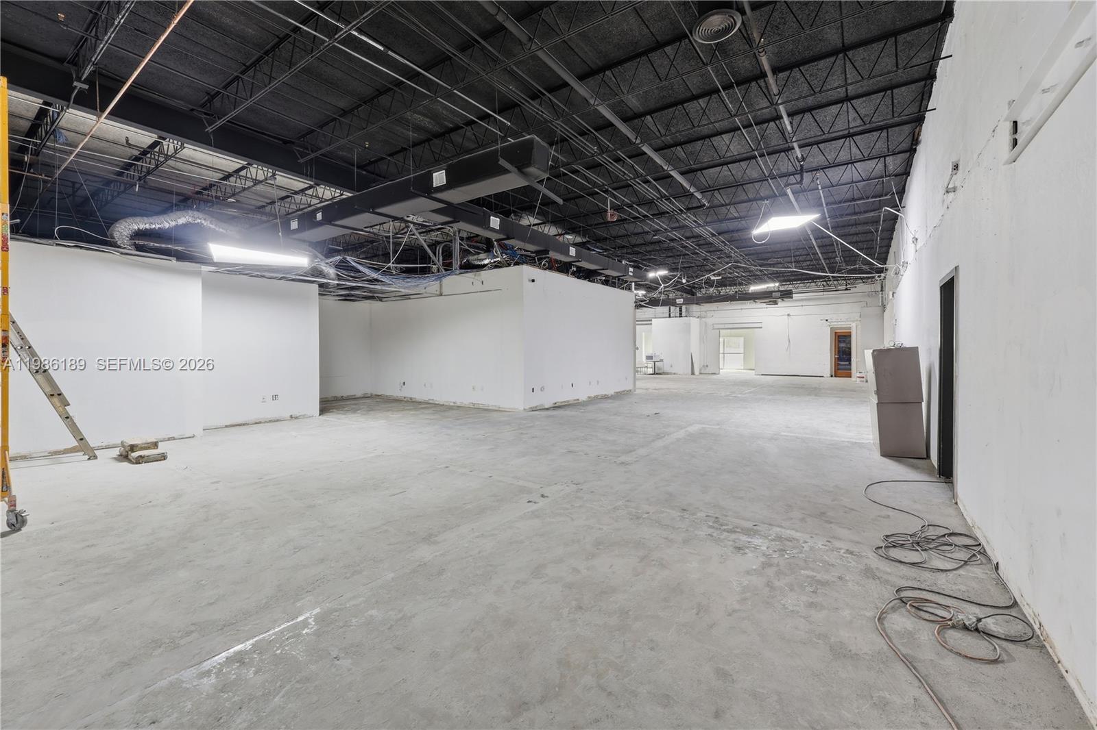 An open-concept commercial space features exposed ceilings, concrete floors, and white partition walls — 2950 N 28th Ter, Hollywood FL 33020, HOLLYWOOD, FL