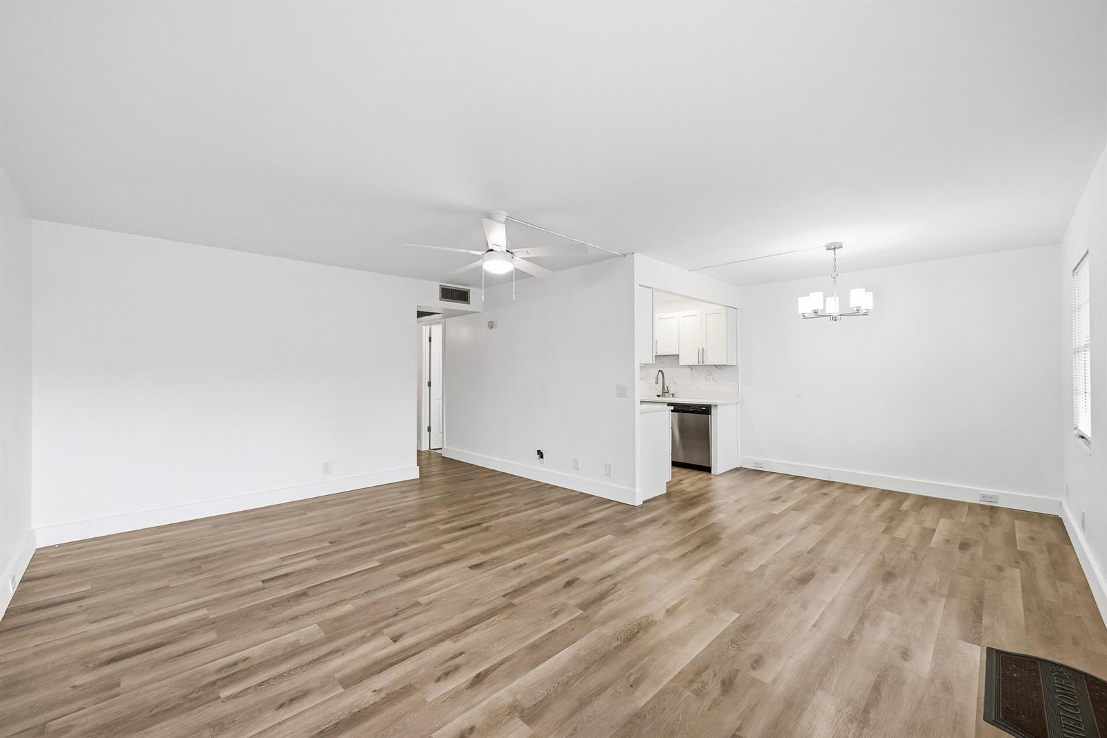 An open-concept living and dining area features white walls and light wood-look flooring — 1043 Cornwall C, Boca Raton FL 33434, BOCA RATON, FL