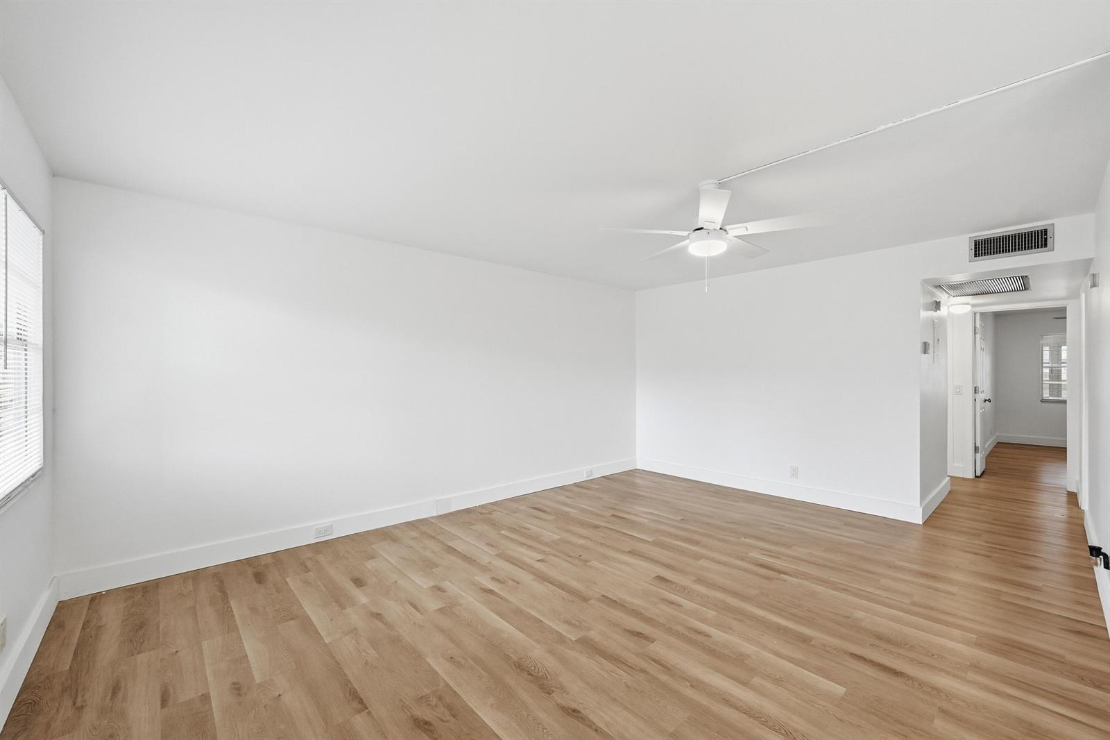 An empty room with white walls, light wood flooring, and a ceiling fan — 1043 Cornwall C, Boca Raton FL 33434, BOCA RATON, FL