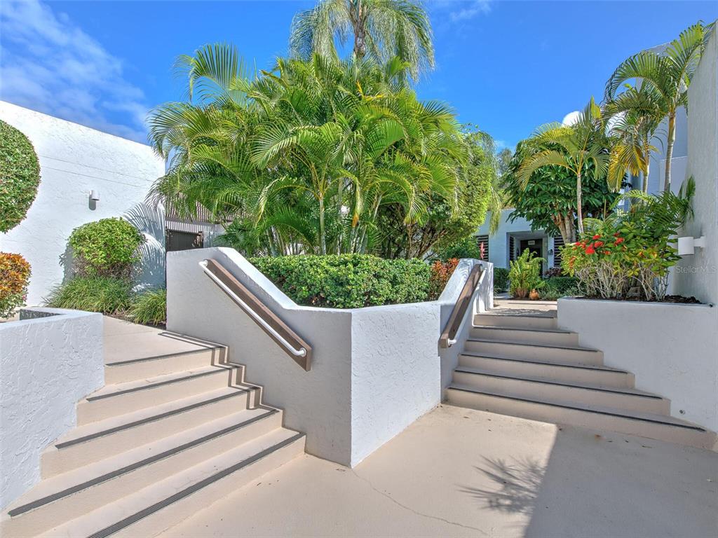 Concrete stairs with handrails lead to an entrance surrounded by lush tropical landscaping — 517 BAYPORT WAY UNIT 517, LONGBOAT KEY, FL
