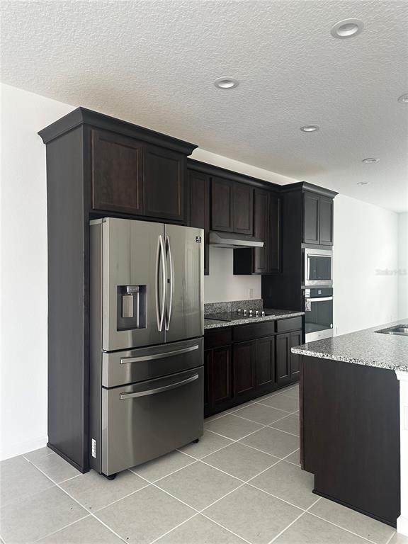 A kitchen features dark wood cabinets, stainless steel appliances, and granite countertops — 14099 LOCHEND WAY, WINTER GARDEN, FL
