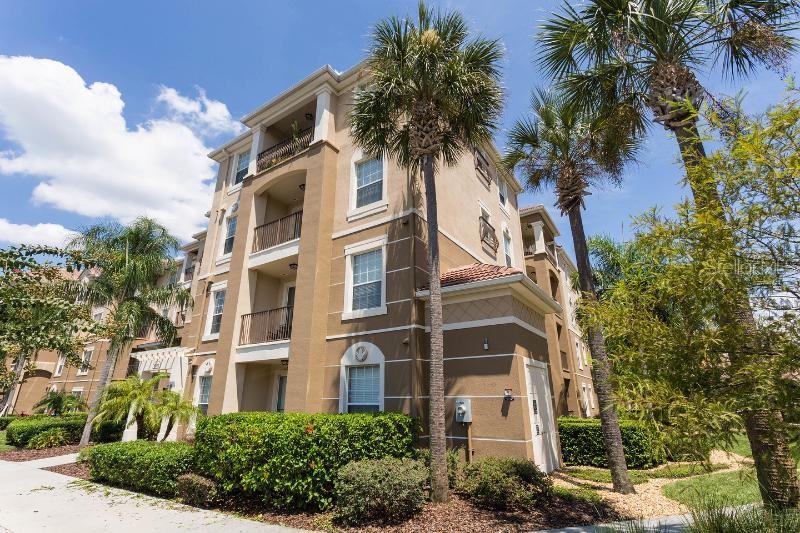 A multi-story tan apartment building with balconies and palm trees under a blue sky — 5000 CAYVIEW AVENUE UNIT 309, ORLANDO, FL