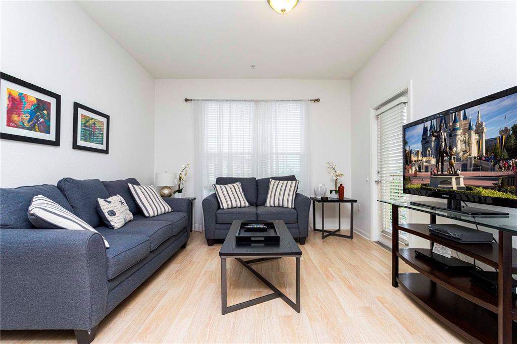 A living room features a blue sofa, a loveseat, a coffee table, and a television — 5000 CAYVIEW AVENUE UNIT 309, ORLANDO, FL