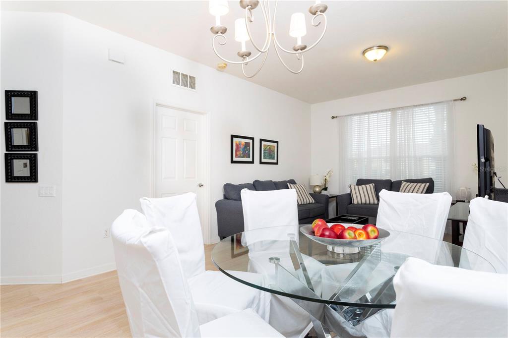 A dining area with a glass table and white chairs sits before a living room — 5000 CAYVIEW AVENUE UNIT 309, ORLANDO, FL