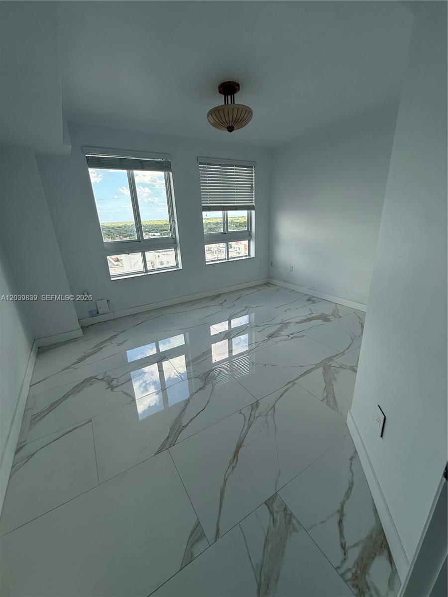 An empty room features white marble-look tile flooring, two windows with blinds, and a ceiling light — 7350 SW 89th St # 1602S, Miami FL 33156, MIAMI, FL