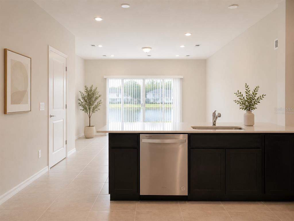 A kitchen island with a stainless steel dishwasher faces a room with sliding glass doors — 4576 SPARKLING SHELL AVENUE, KISSIMMEE, FL