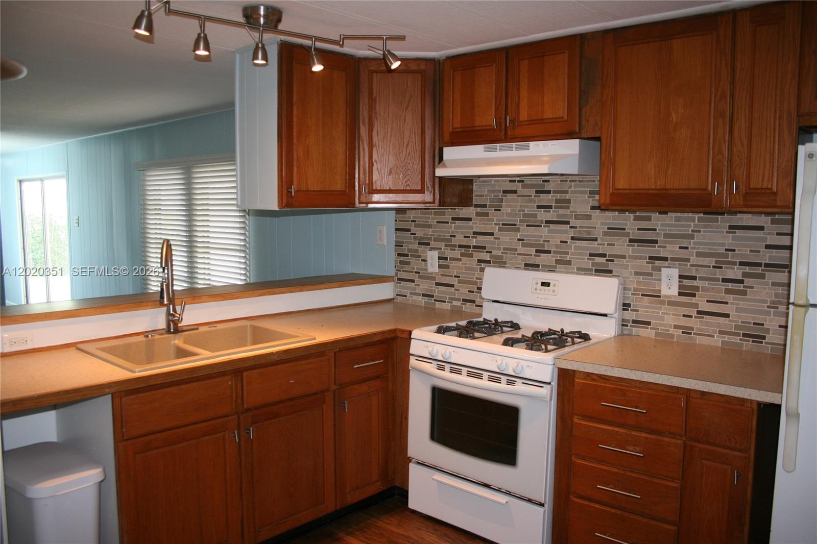 A kitchen features wood cabinets, a white stove, a tiled backsplash, and a double sink — 13 Old State Rd, Key Largo FL 33037, KEY LARGO, FL