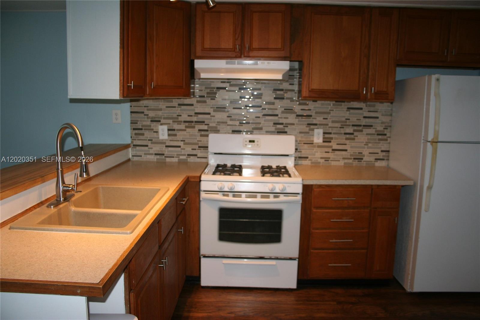 A kitchen features wood cabinets, a white stove, a tiled backsplash, and a double sink — 13 Old State Rd, Key Largo FL 33037, KEY LARGO, FL