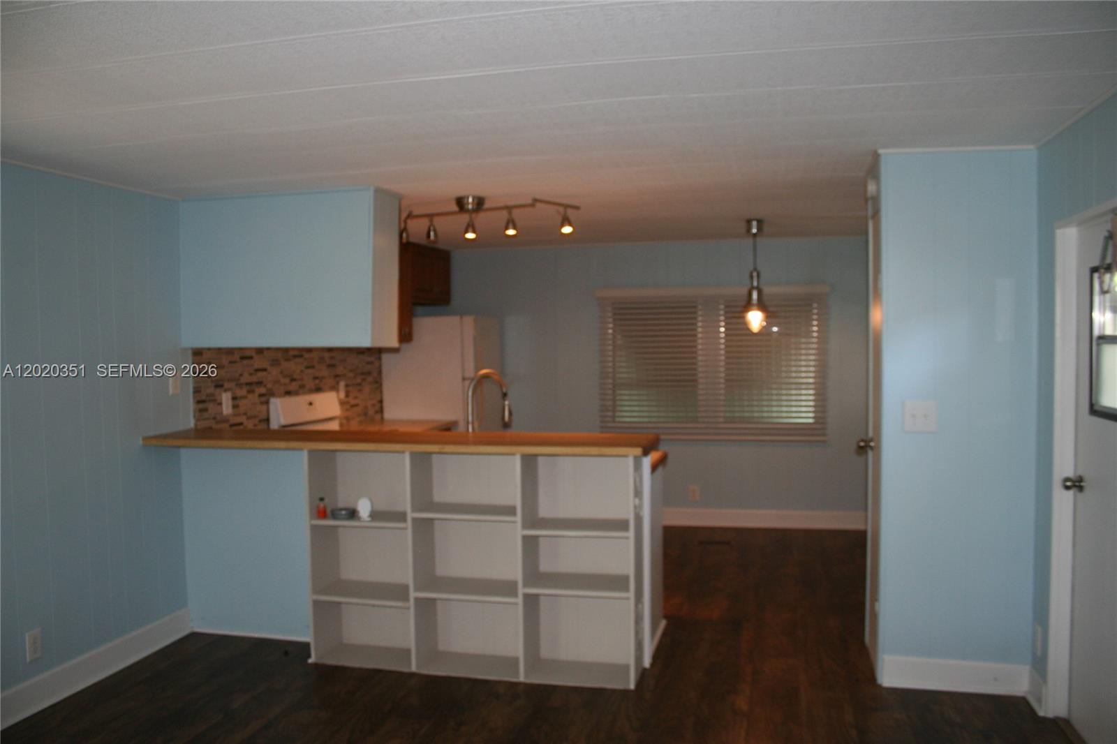 A kitchen features a wooden breakfast bar with built-in shelving and light blue walls — 13 Old State Rd, Key Largo FL 33037, KEY LARGO, FL
