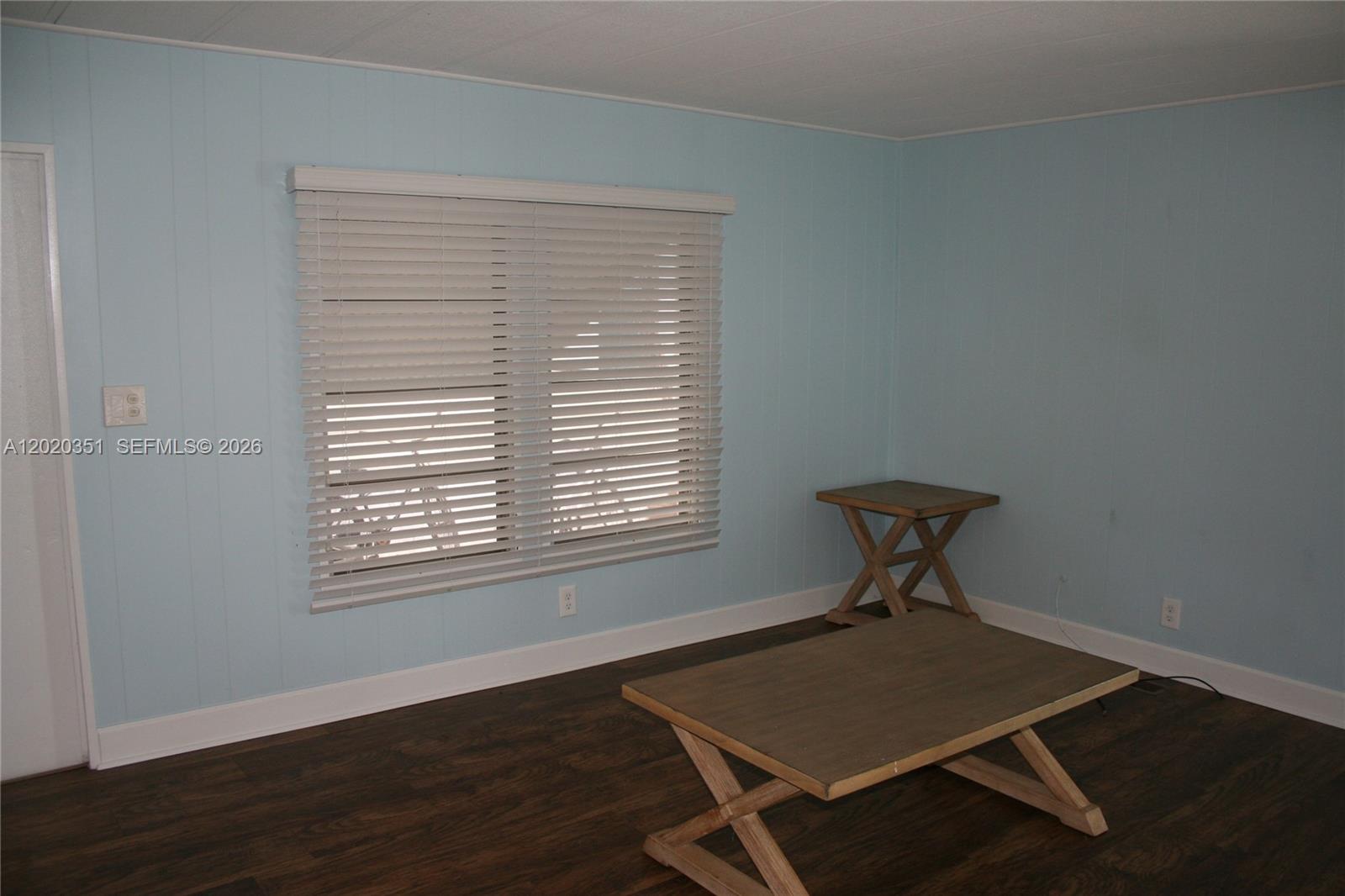 A room with light blue paneled walls, dark wood flooring, and two wooden tables — 13 Old State Rd, Key Largo FL 33037, KEY LARGO, FL