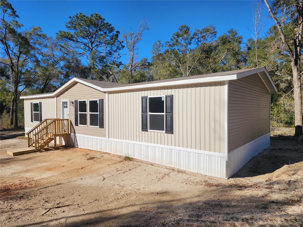 A single-story manufactured home with tan siding sits on a grassy lot near trees — 7513 W DUNKLIN STREET, DUNNELLON, FL
