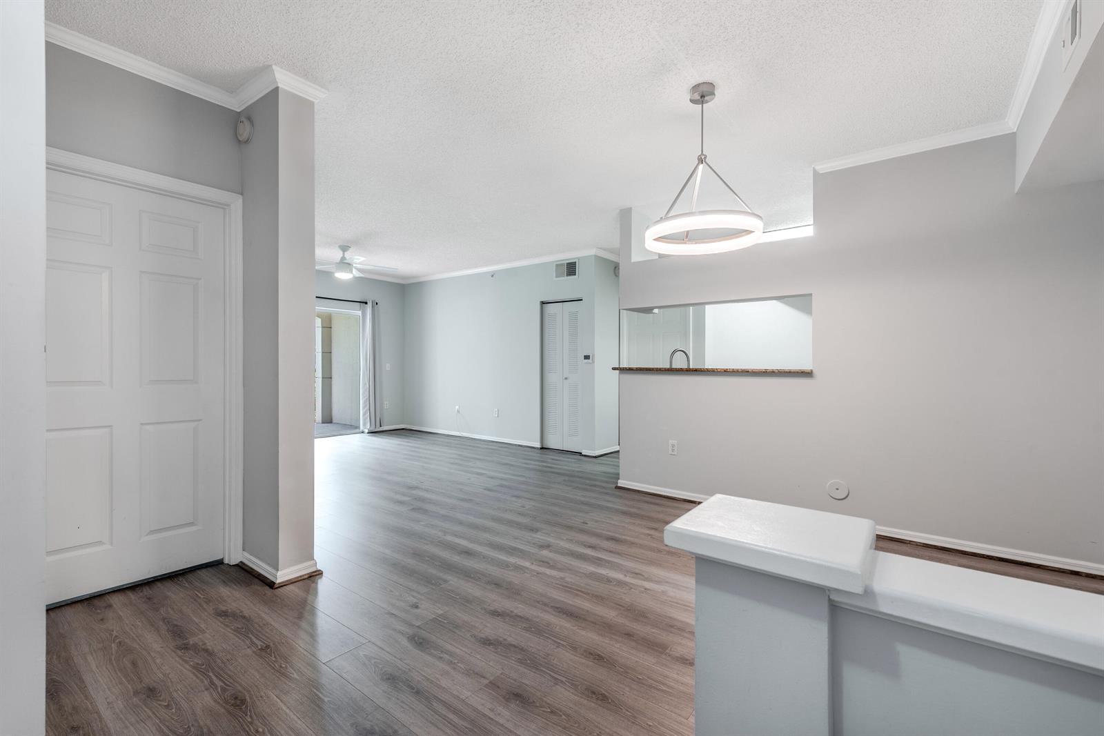 An open-concept living area features light gray walls, wood-look flooring, and a modern pendant light — 1106 Tuscany Way, Boynton Beach FL 33435, BOYNTON BEACH, FL