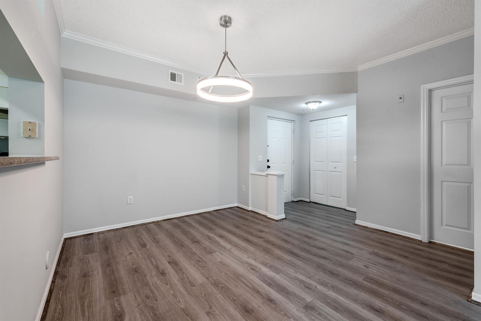 An empty dining area features light gray walls, wood-look flooring, and a modern circular pendant light — 1106 Tuscany Way, Boynton Beach FL 33435, BOYNTON BEACH, FL