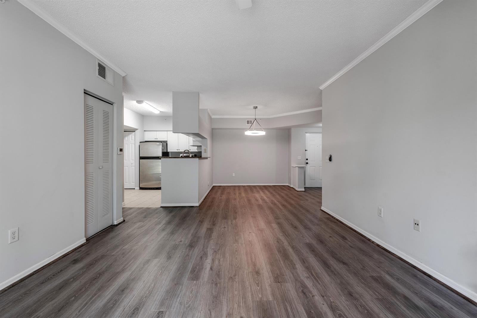 An open-concept living and dining area features wood-look flooring, light gray walls, and a kitchen — 1106 Tuscany Way, Boynton Beach FL 33435, BOYNTON BEACH, FL