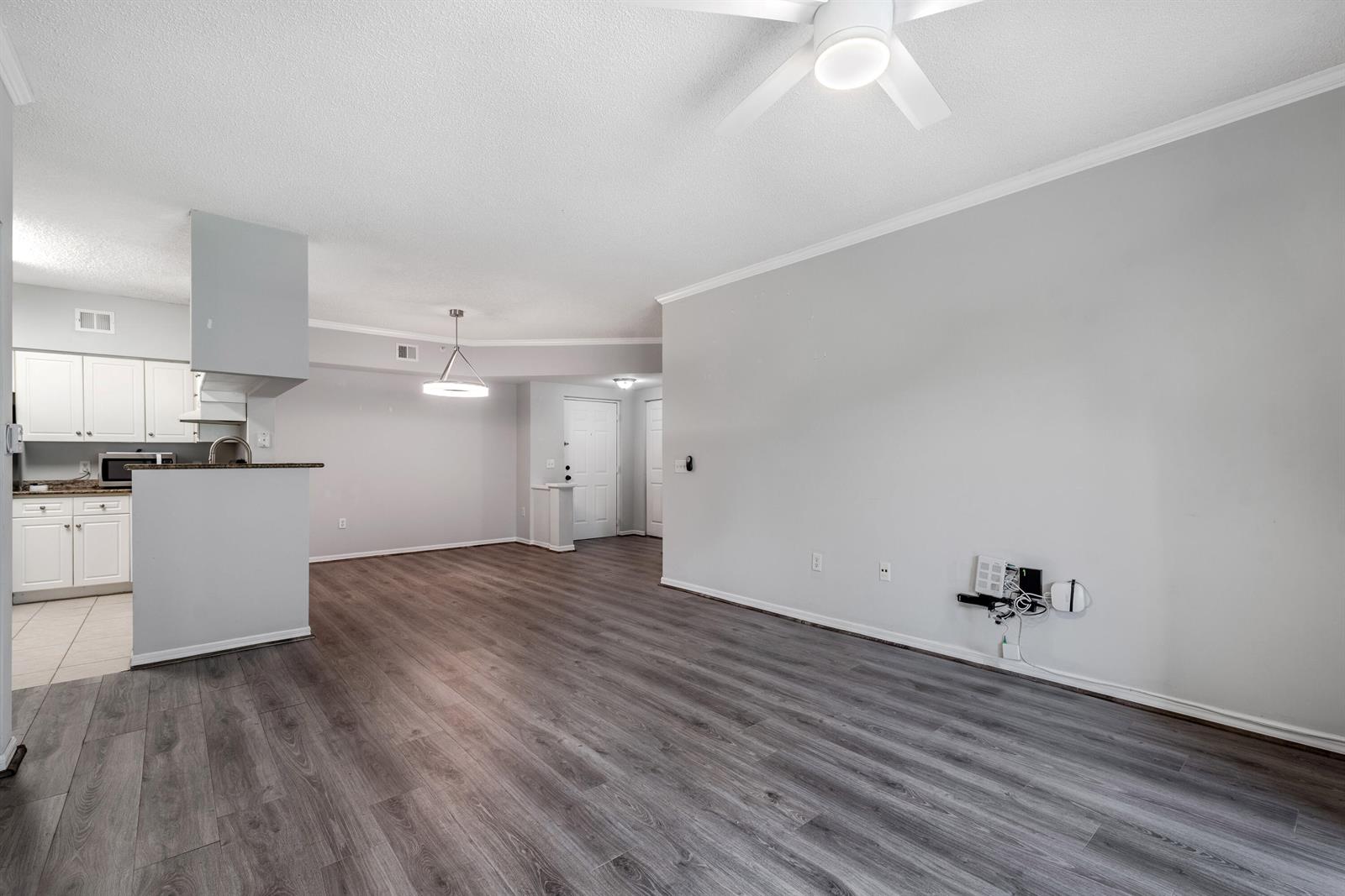 An open-concept living area features gray wood-look flooring, a ceiling fan, and an adjacent kitchen — 1106 Tuscany Way, Boynton Beach FL 33435, BOYNTON BEACH, FL