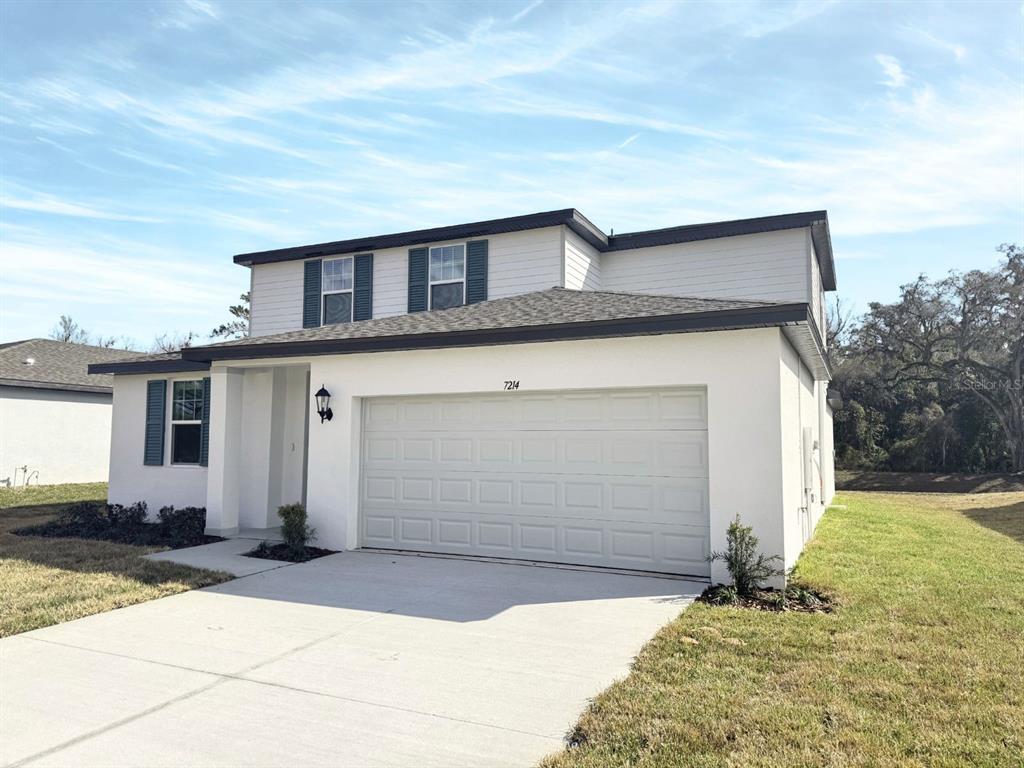 A two-story house with a white stucco facade, a two-car garage, and dark shutters — 7214 RAY CREEK DRIVE, BROOKSVILLE, FL