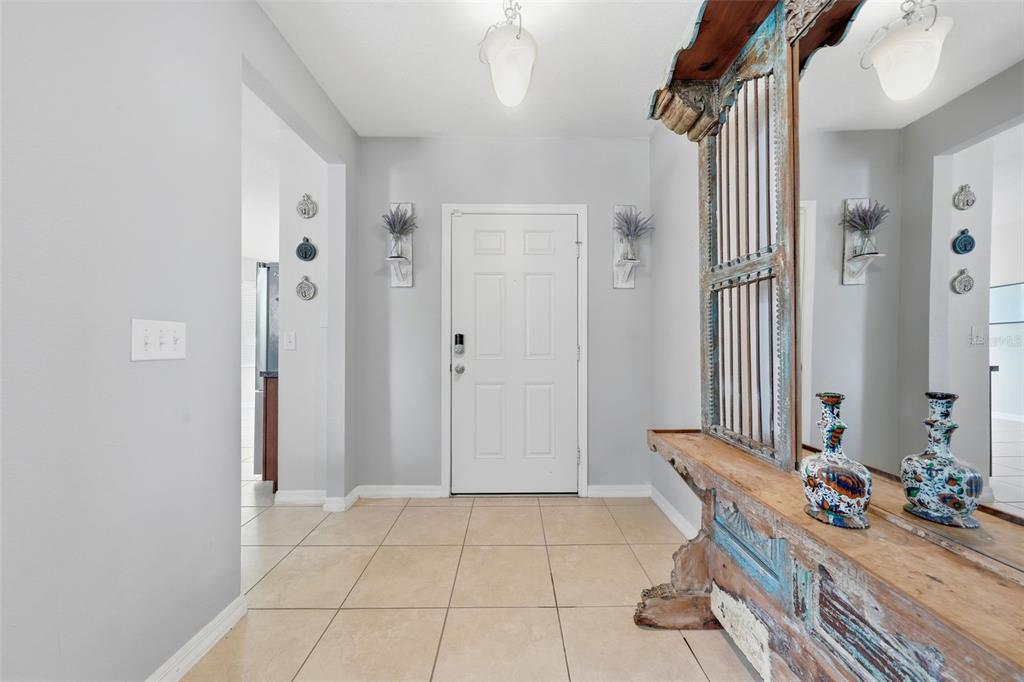 An entryway features a white front door, light gray walls, tile flooring, and a wooden console — 940 FALLBROOKE AVENUE, DELTONA, FL