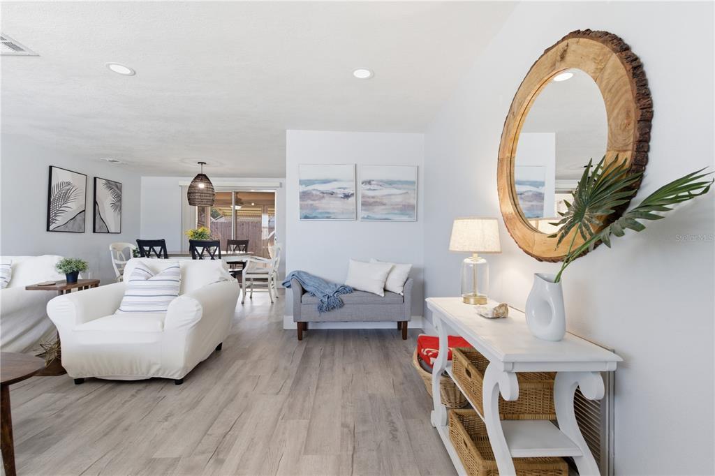 A living room features light wood flooring, a white console table, and a round mirror — 7608 SUE ELLEN DRIVE, PORT RICHEY, FL