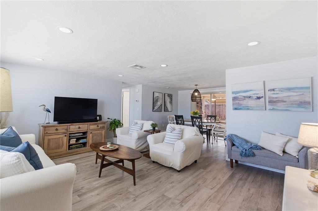 A living room with light wood floors, white furniture, and a wooden media console — 7608 SUE ELLEN DRIVE, PORT RICHEY, FL