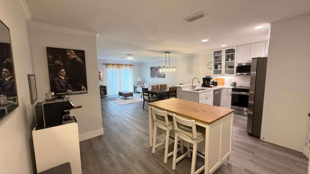 An open-concept kitchen and dining area features white cabinetry, a wooden island, and gray flooring — 5073 KINGSCREST LANE, OVIEDO, FL