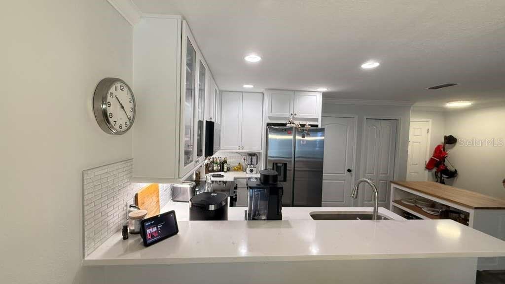 A kitchen features white cabinetry, stainless steel appliances, a quartz countertop, and a breakfast bar — 5073 KINGSCREST LANE, OVIEDO, FL