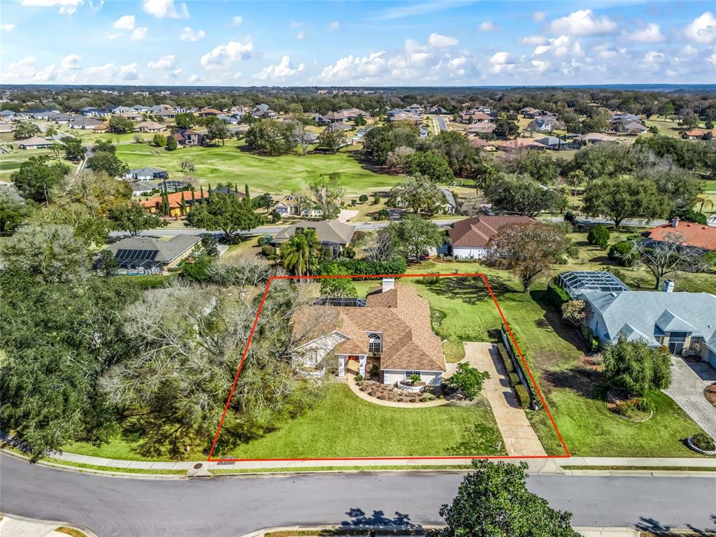 An aerial view shows a single-story house with a brown roof on a corner lot — 5321 GREENS DRIVE, LADY LAKE, FL