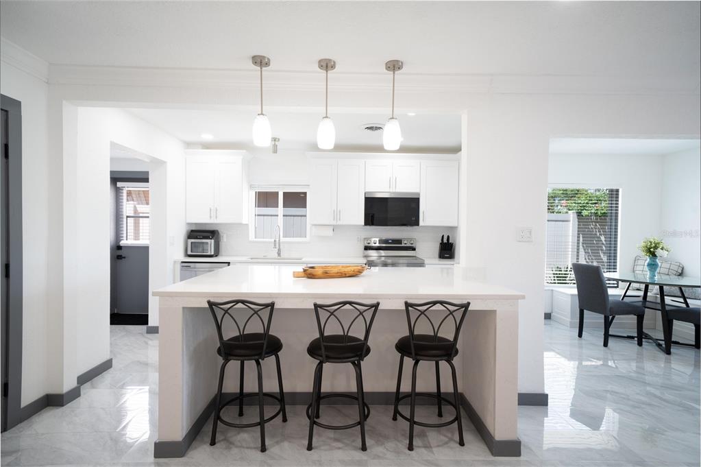 A bright entryway features white tile floors, a blue armchair, and two beach-themed wall canvases — 166 BAYSIDE DRIVE, CLEARWATER BEACH, FL