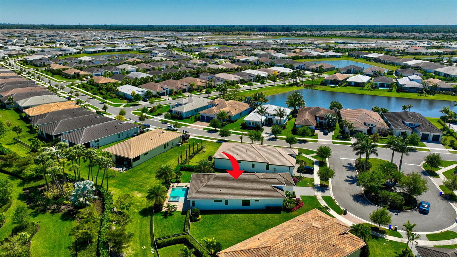 An aerial view of a suburban neighborhood featuring a house with a red arrow pointing down — 15808 Amelia Terrace, Westlake FL 33470, WESTLAKE, FL