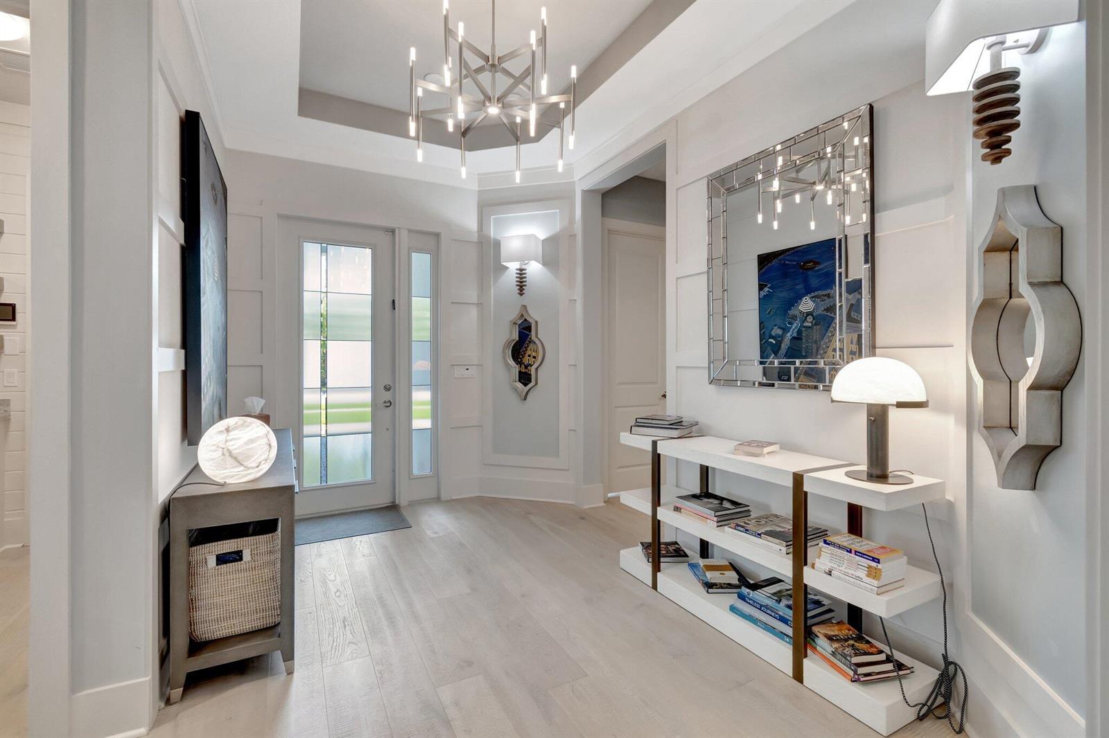 A bright entryway features light wood floors, a modern chandelier, and white paneled walls — 15808 Amelia Terrace, Westlake FL 33470, WESTLAKE, FL