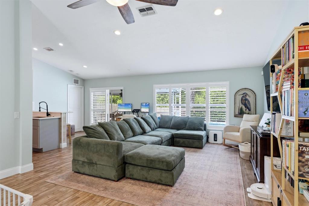 A living room features a large green sectional sofa, a rug, and a bookshelf — 306 111TH STREET E, BRADENTON, FL