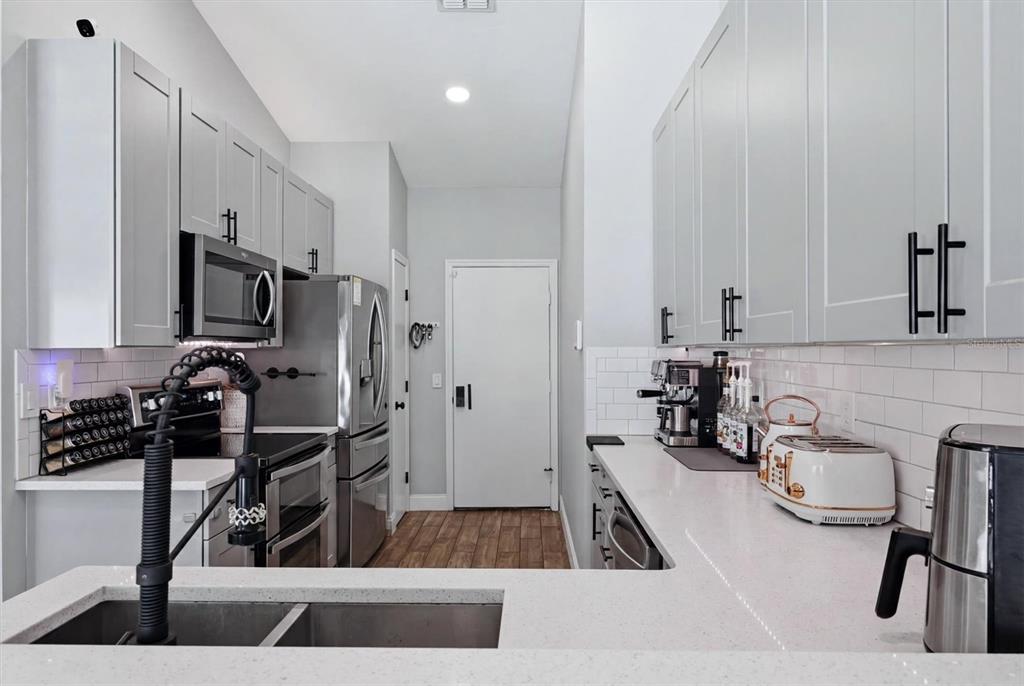A modern kitchen features gray cabinets, white countertops, stainless steel appliances, and subway tile backsplashes — 306 111TH STREET E, BRADENTON, FL