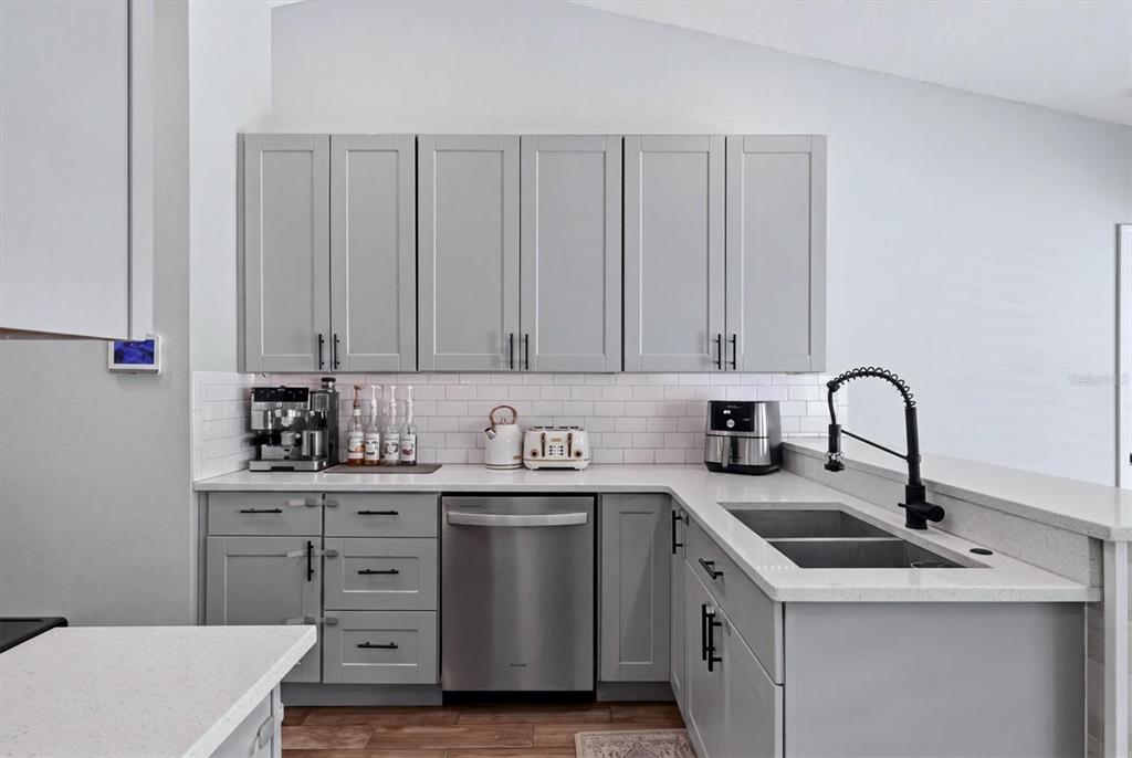 A kitchen features gray shaker cabinets, white countertops, a subway tile backsplash, and stainless appliances — 306 111TH STREET E, BRADENTON, FL