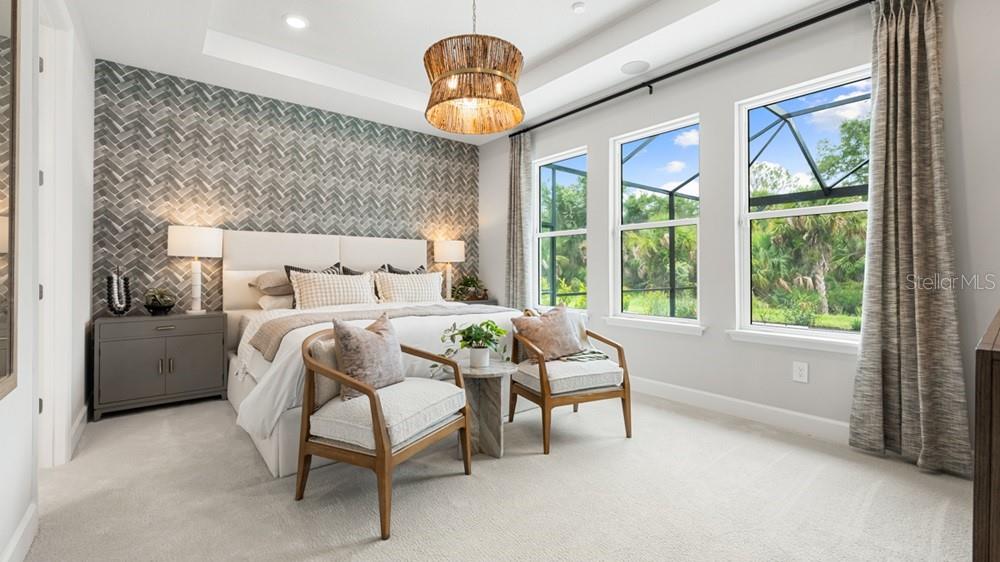A bedroom features a herringbone accent wall, a tray ceiling, and three windows overlooking greenery — 12751 DOCKYARD TRAIL, PALMETTO, FL