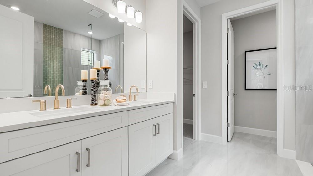 A modern bathroom features a white double vanity with gold faucets and a large mirror — 12751 DOCKYARD TRAIL, PALMETTO, FL