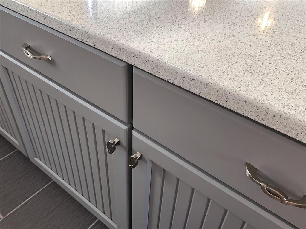 A close-up view of gray beadboard cabinets with silver hardware and a speckled countertop — 896 RADCLIFE BEREA PLACE, THE VILLAGES, FL