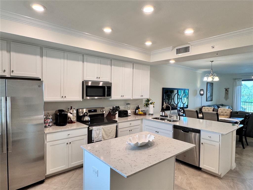 A modern kitchen features white cabinets, stainless steel appliances, and a central island with countertops — 17724 GAWTHROP DRIVE UNIT 304, BRADENTON, FL