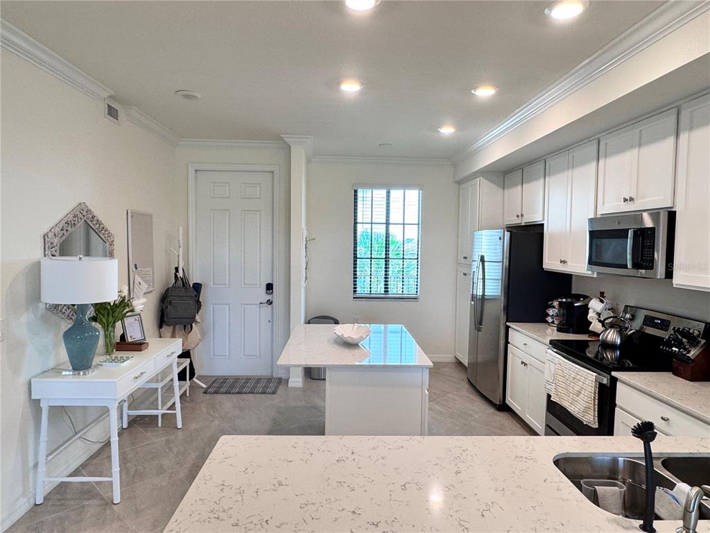 A kitchen features white cabinets, stainless steel appliances, a center island, and a dining area — 17724 GAWTHROP DRIVE UNIT 304, BRADENTON, FL